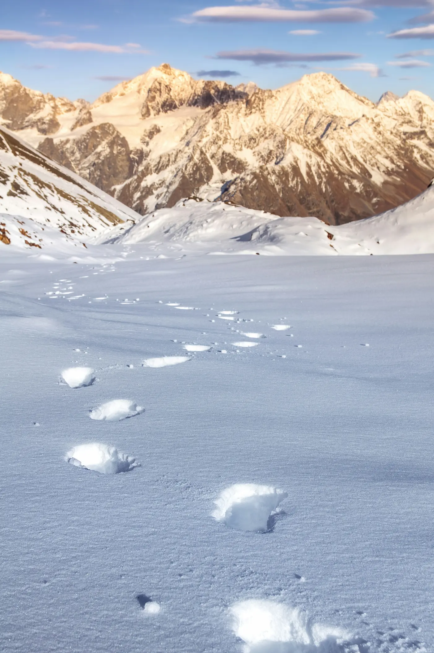 Winding footprints on the snow with mountains in the background